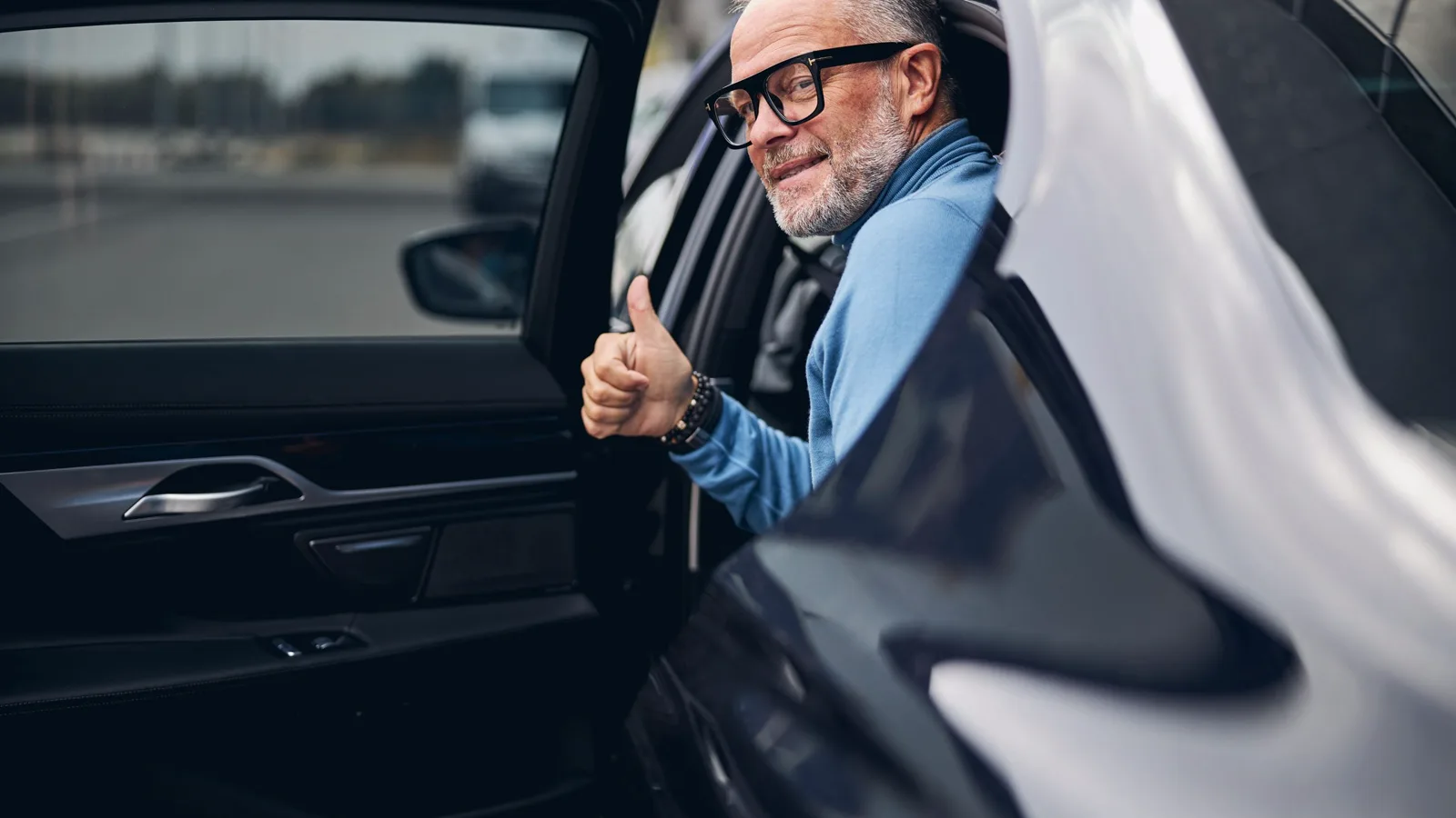 A passenger stepping out of a black executive saloon on arrival