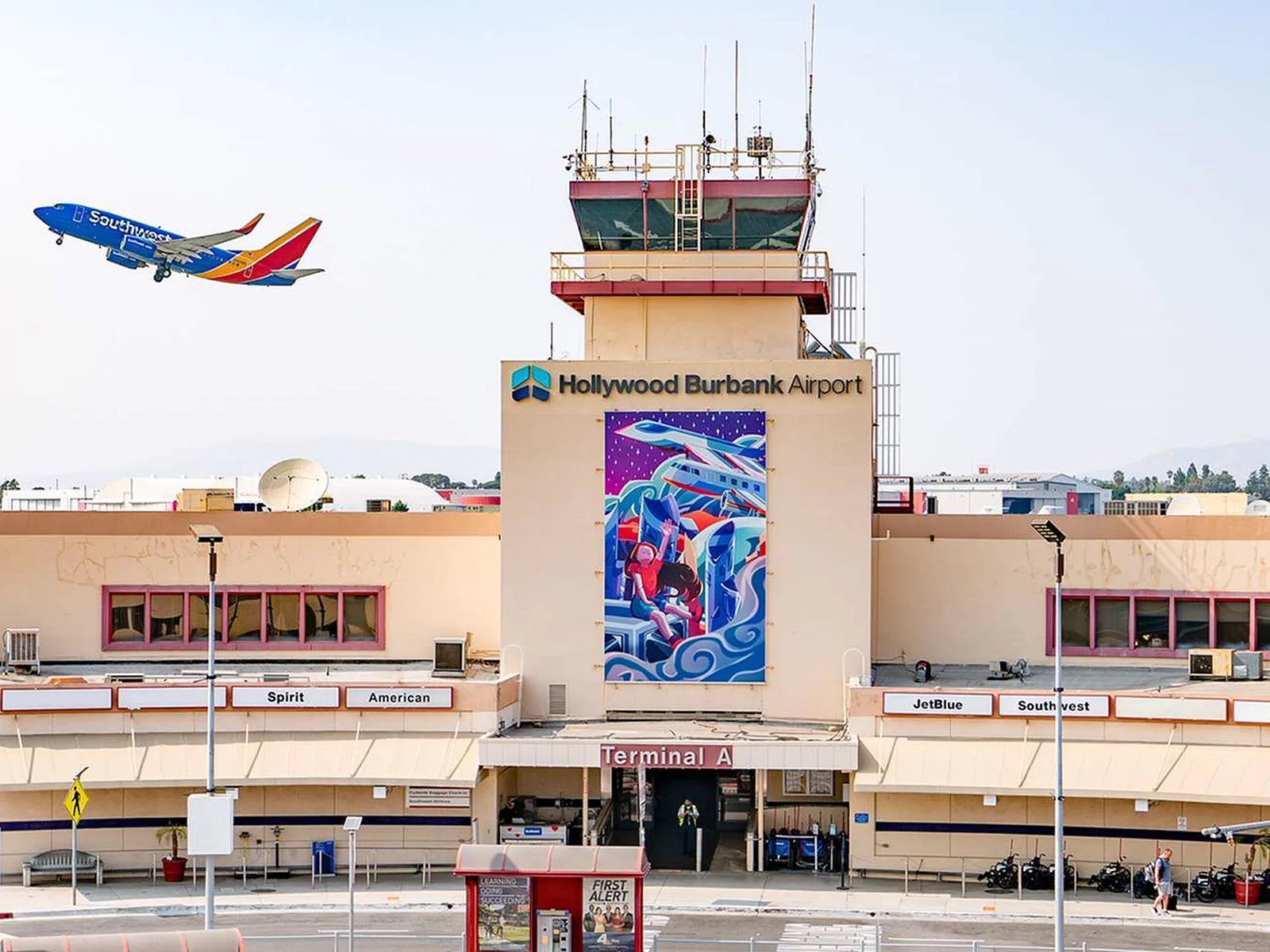 Terminal A at Hollywood Burbank Airport with a Southwest jet climbing above the control tower